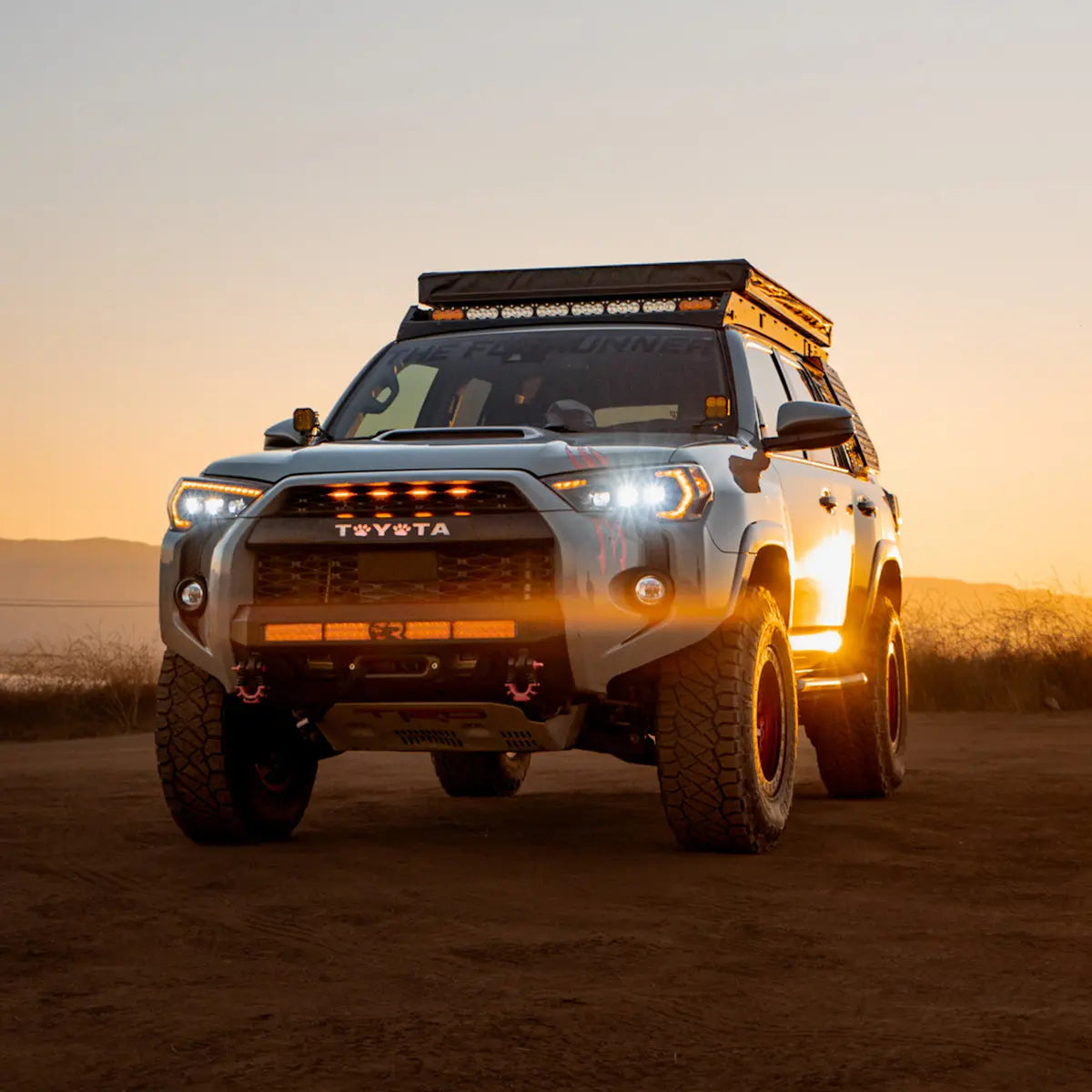 Toyota 4Runner 5th Gen with Cali Raised LED Premium Roof Rack and full front light bar setup lit up at sunset
