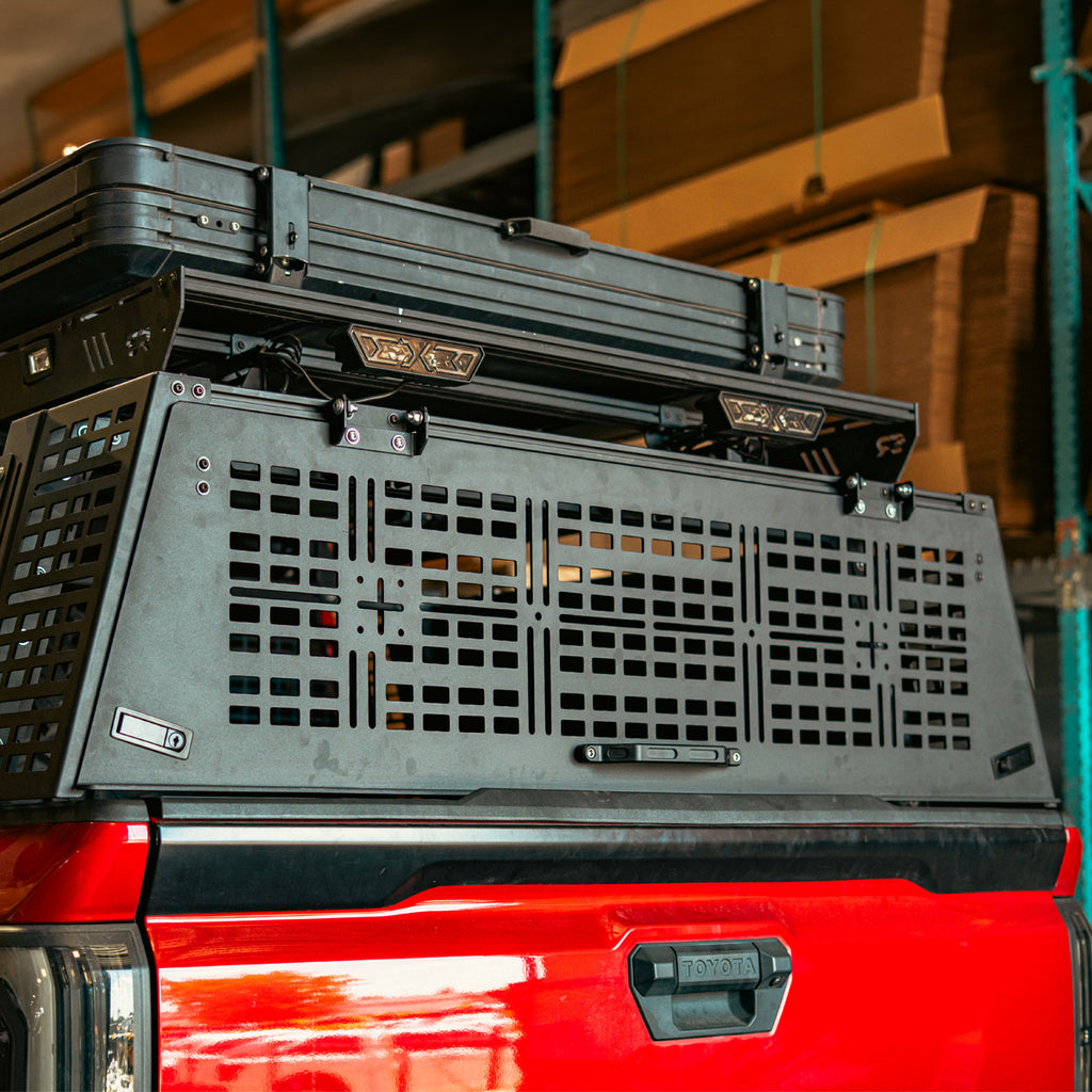 Rear hatch with latches and handle closed on a red Toyota Tacoma overland bed rack
