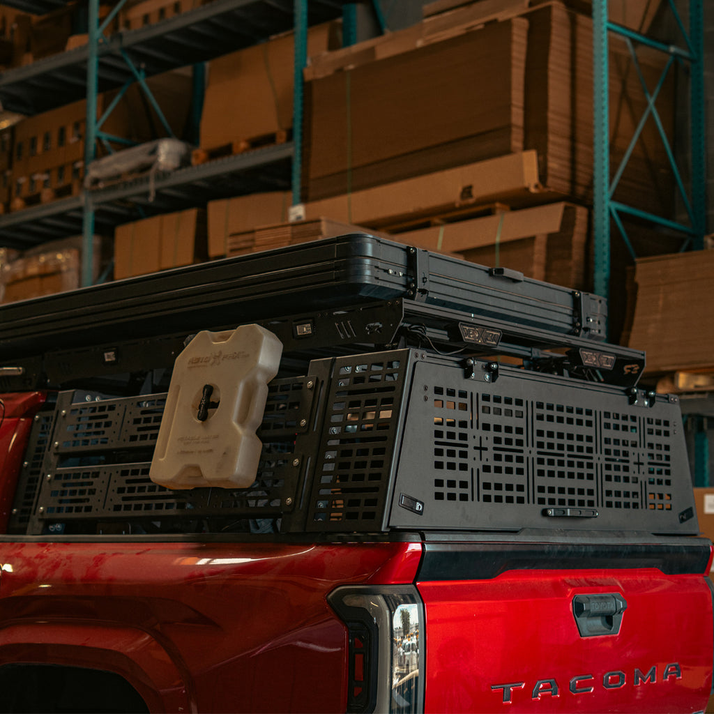 Rear quarter view of a red Toyota Tacoma with the bed rack rear hatch and MOLLE side panels