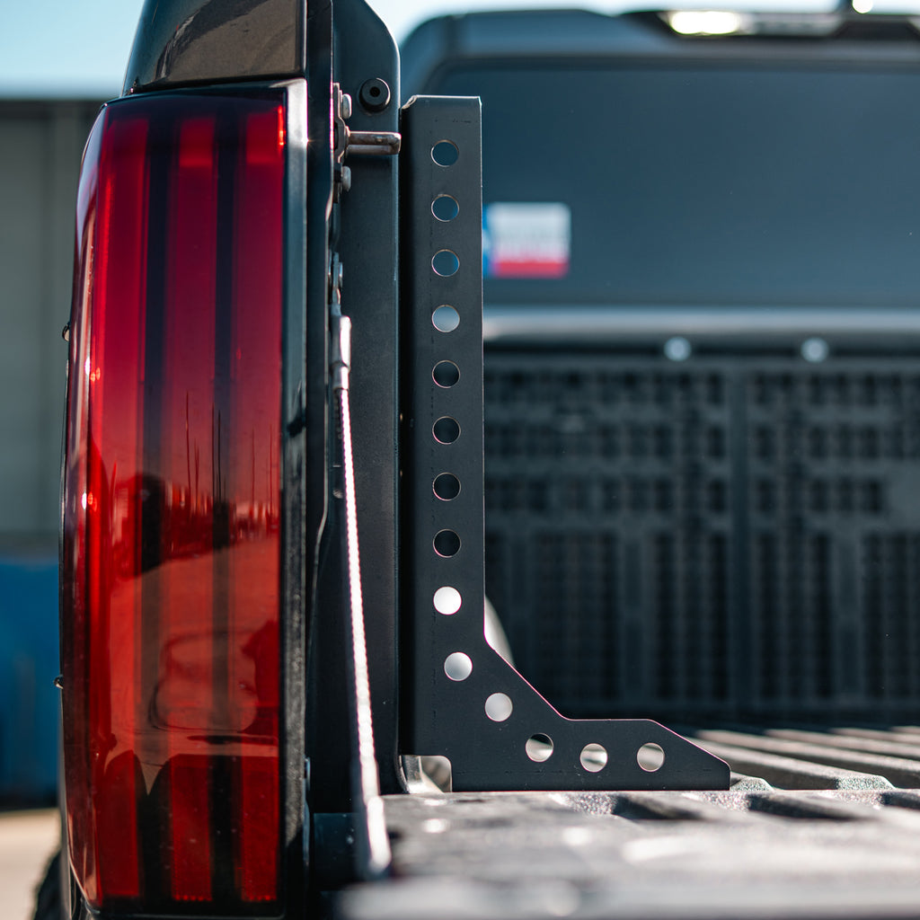 Rear view of a Cali Raised LED bed stiffener beside the taillight and open tailgate on a 2022+ Toyota Tundra.