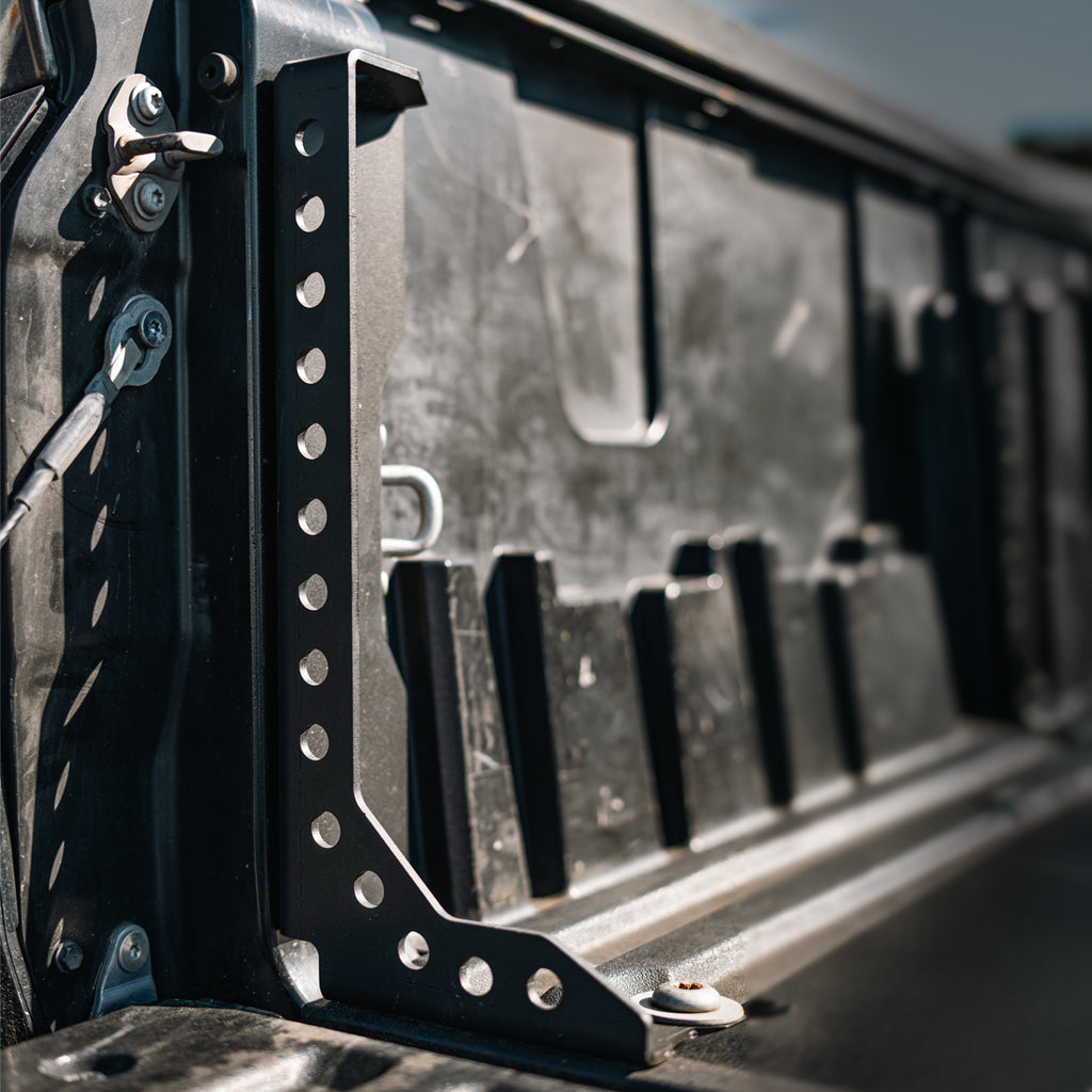 Angled view of a black Cali Raised LED bed support along the composite bed wall of a 2022+ Toyota Tundra.